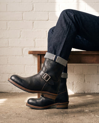 Black 3530 engineer boot seated with legs crossed, outer side and sole edge
