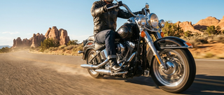 Motorcycle rider wearing engineer boots on a scenic road with desert landscape