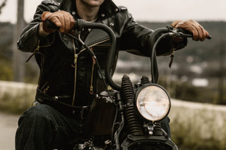 Detail of brown leather gloves on the handlebars of a bobber