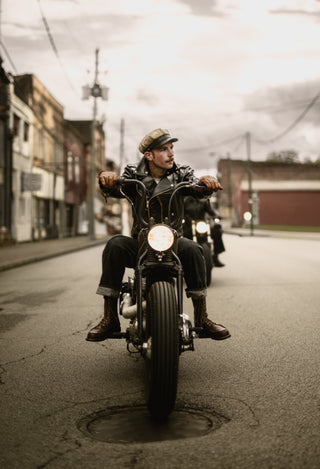 Rider riding straight at camera on main street, brown boots and black leather jacket