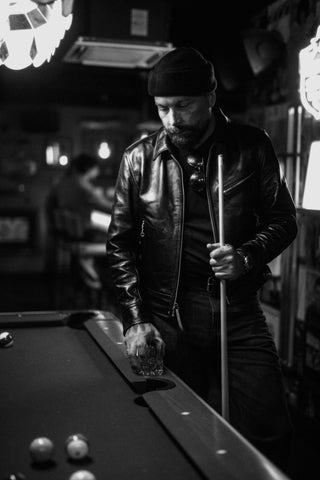 Vertical portrait in the pool hall holding a cue and a glass