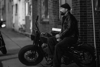 Rider seated on a bobber on a brick-lined street, black and white, photographed by Emerson Kay